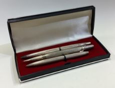 A group of three heavy silver engine turned pencils.