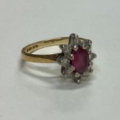 A ruby and diamond daisy head cluster ring set in 18 carat gold.