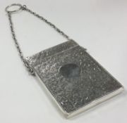 A Victorian silver card case engraved with leaves on suspended chain.