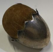A silver plated pin cushion in the form of a cracked egg.