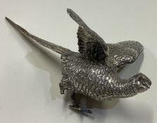 A silver figure of a pheasant with outstretched wings.