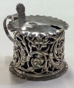 A chased Victorian silver mustard pot with pierced decoration.