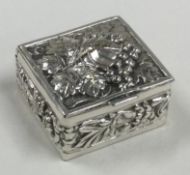 A chased silver pill box embossed with vine decoration.