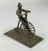 An Antique silver toy figure of a man on a Penny Farthing.