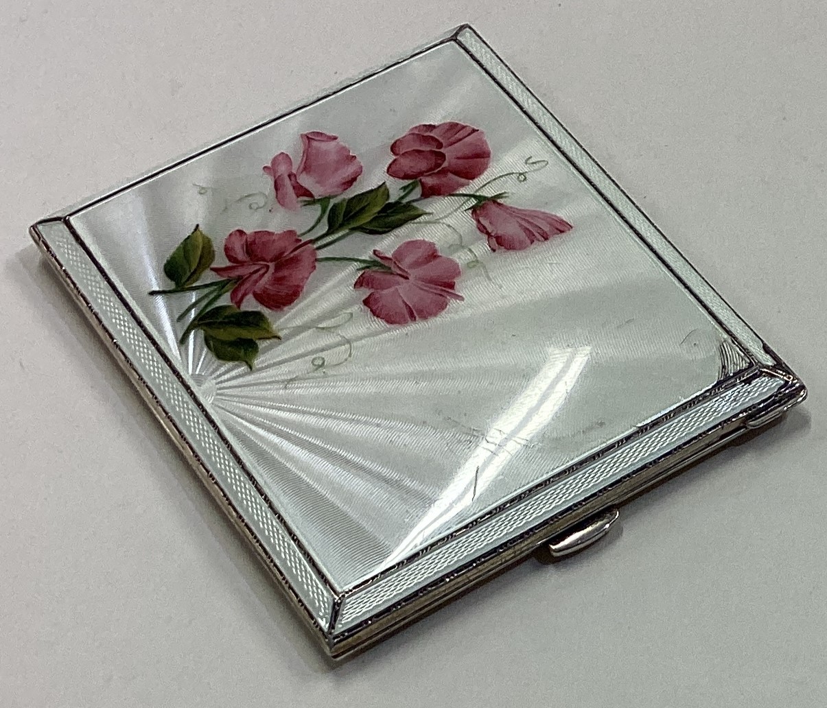 A silver and enamelled cigarette case decorated with flowers.