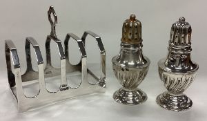 A silver toast rack together with a pair of peppers.