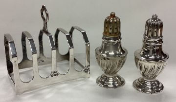 A silver toast rack together with a pair of peppers.