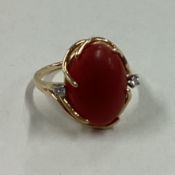 A coral and diamond three stone ring in 14 carat gold mount.