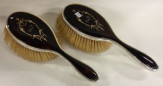 A pair of silver and tortoiseshell inlaid brushes.