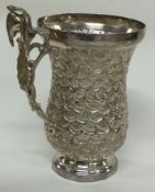 An Antique Continental silver mug with figural handle and embossed with shells.