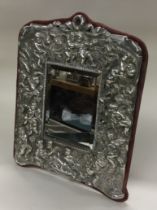 A silver backed mirror embossed with cherubs.