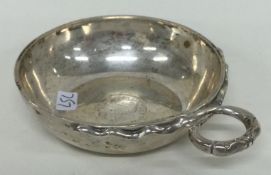 A heavy silver wine taster with coin to centre.
