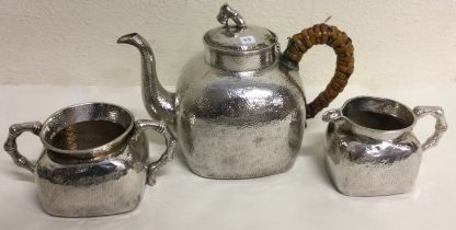 A Chinese export silver three piece tea set of hammered design. Marked to base.