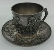 A Chinese export chased silver teacup on stand. Circa 1900.