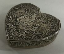 A heavy silver heart shaped pill box with chased decoration.