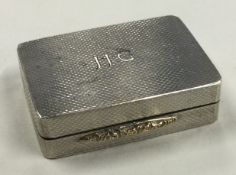 A silver pill box with hinged lid and engine turned decoration.
