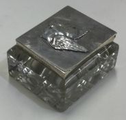 A silver and glass stamp case embossed with cherubs.