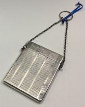 A silver engine turned card case on suspended chain.