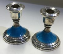 A pair of silver and blue enamelled candlesticks.