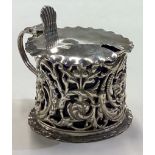 A chased Victorian silver mustard pot with pierced decoration.