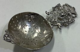 A Continental silver tea strainer embossed with flowers.