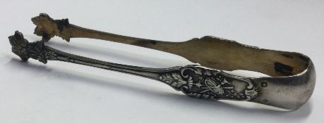 A pair of silver claw ice tongs chased with floral decoration.