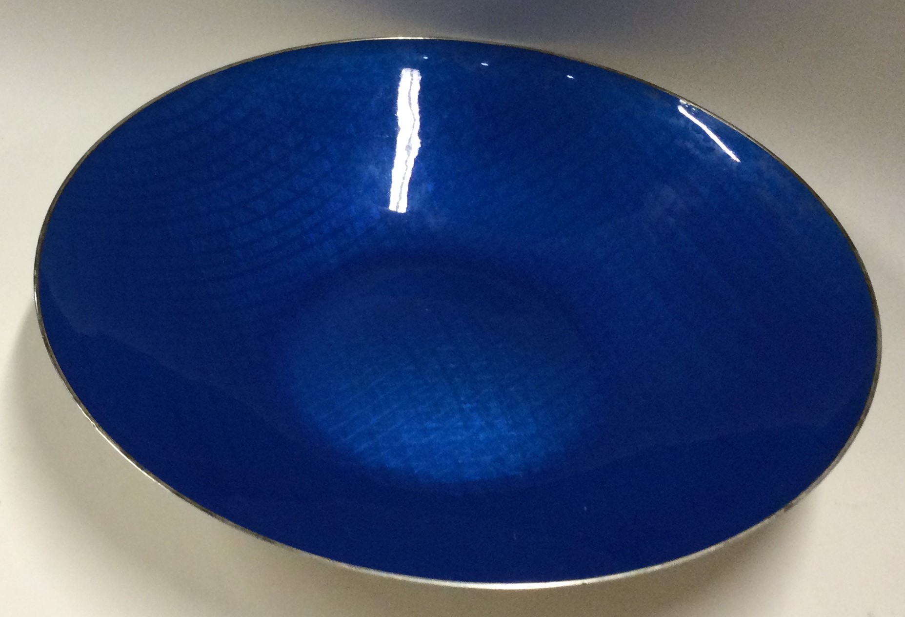 A large circular silver and blue enamelled dish.