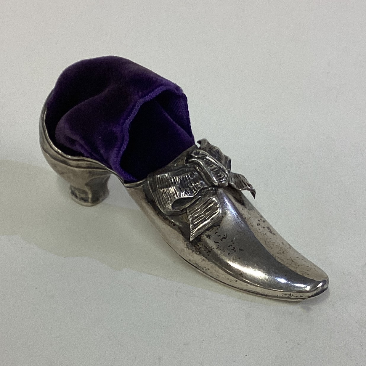 A Victorian silver pin cushion in the form of a shoe.