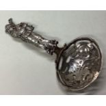 A silver sifter spoon with figural handle.
