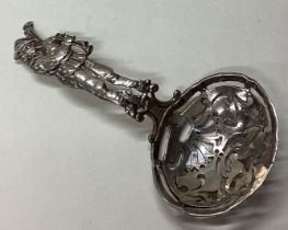 A silver sifter spoon with figural handle.