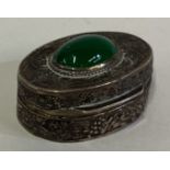 A Continental silver pill box with green stone decoration.