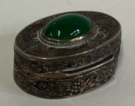 A Continental silver pill box with green stone decoration.