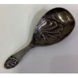 A silver caddy spoon with fluted shell design.