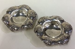 A pair of ornate American silver dishes on feet.