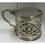 A large pierced silver mustard pot with hinged lid.
