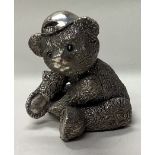 A novelty silver figure of a teddy bear wearing a cap.