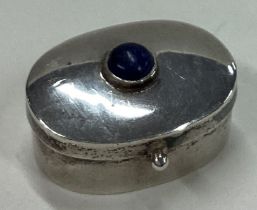 A silver pill box with hinged lid and stone decoration.