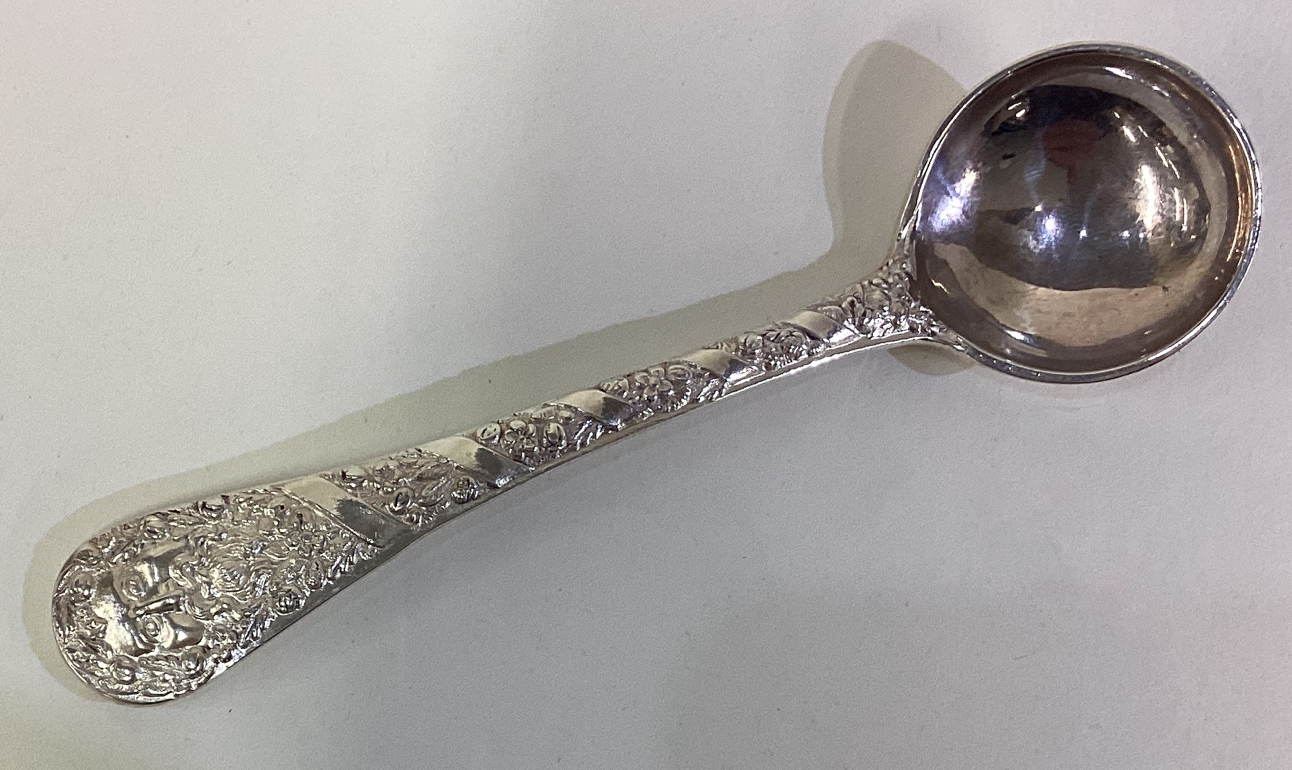 A silver mustard spoon embossed with figural and foliage decoration. - Image 2 of 2