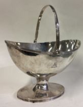 A large George III silver swing handled basket with crested decoration.