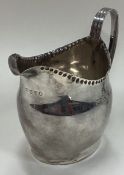 A George III silver cream jug with beaded border.