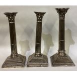 A heavy pair of silver Corinthian column candlesticks of typical form together with one other.