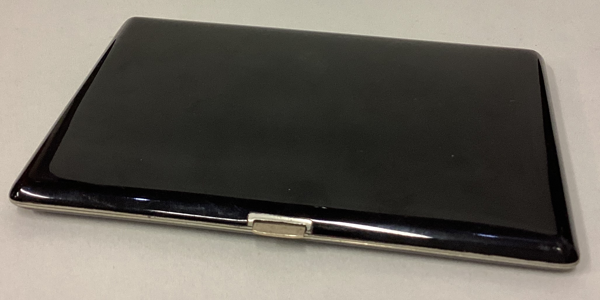 A large silver plated and black enamelled cigarette case.