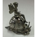 A white metal box with hinged lid in the form of a snail with fairy on top.