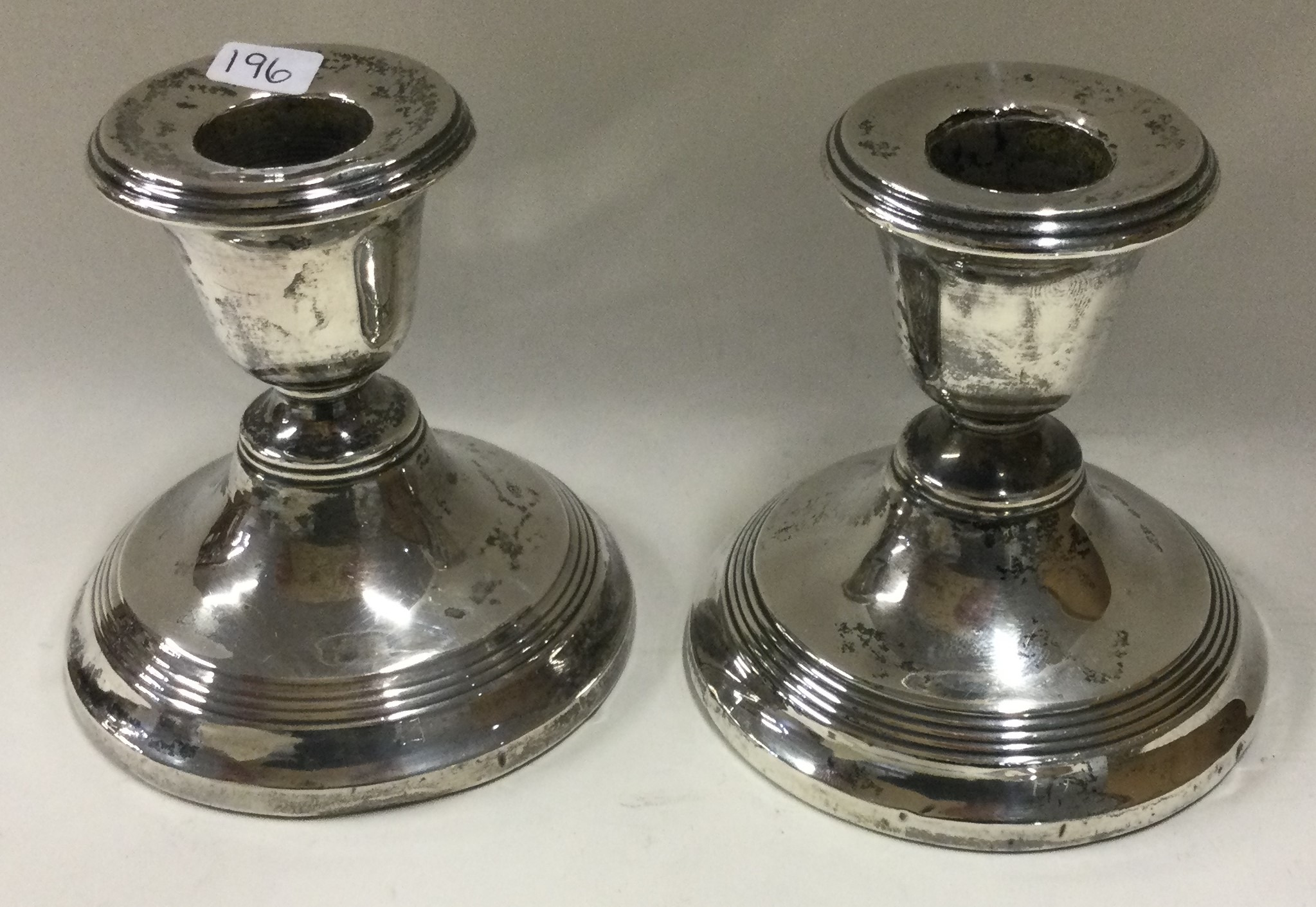 A pair of circular silver piano candlesticks.