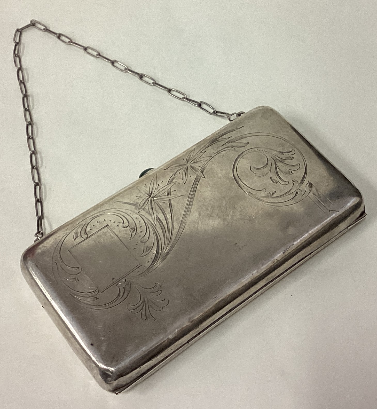 A large Russian silver purse with green stone and engraved decoration.