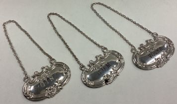 A set of three silver wine labels on suspension chains.