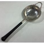 A heavy silver tea strainer with ebony handle and pierced decoration.