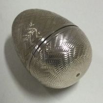 A silver pill box in the form of an egg.