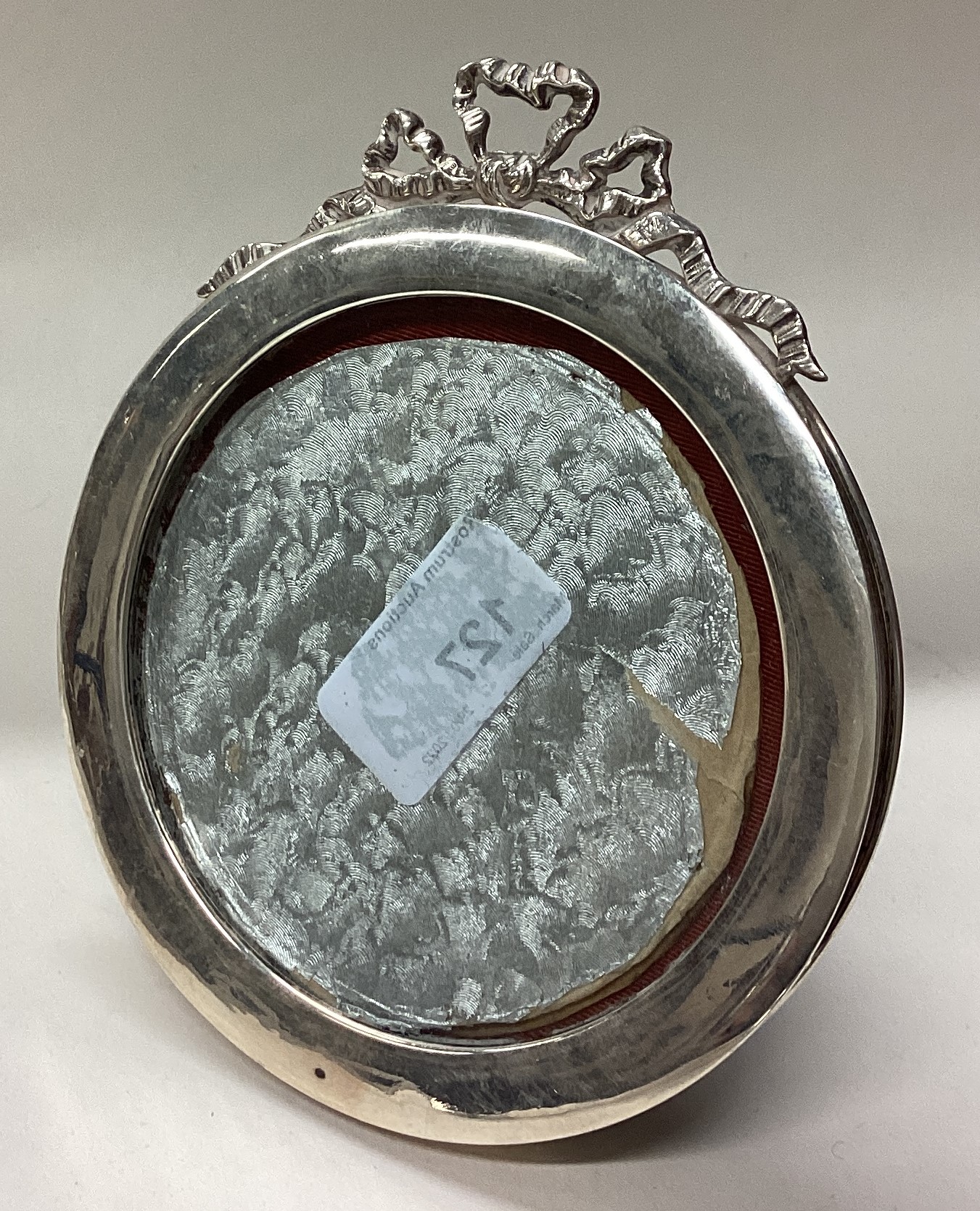 A circular silver picture frame with swag decoration.