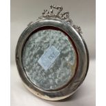 A circular silver picture frame with swag decoration.